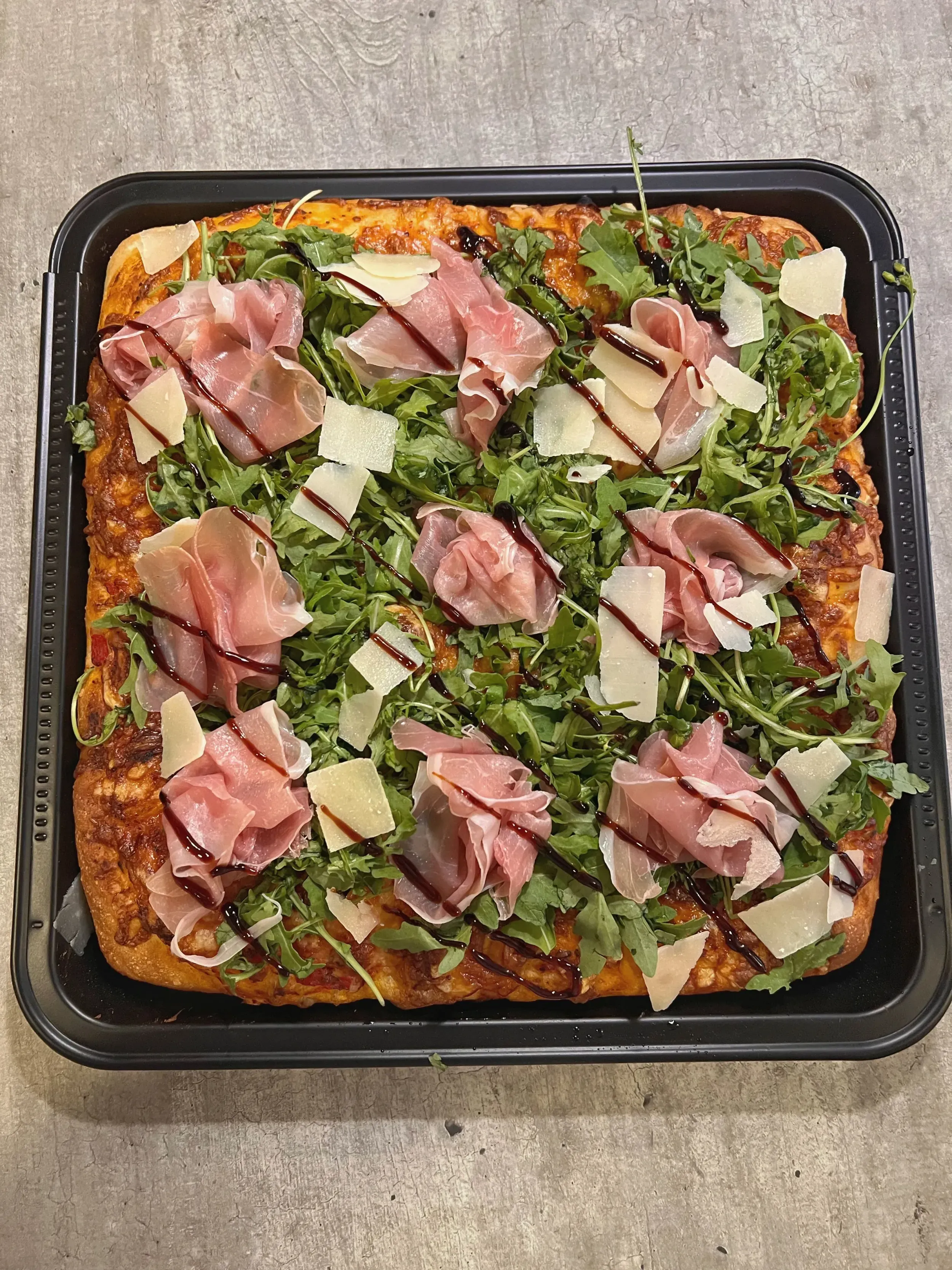 pizza al taglio prosciuttóval és rukkolával