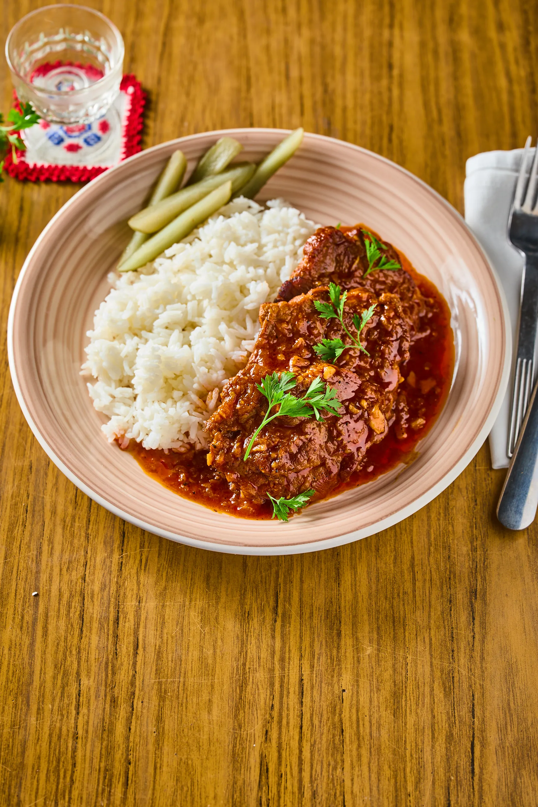 Fokhagymás-paprikás sertéstarja rizzsel, uborkával, tányérban