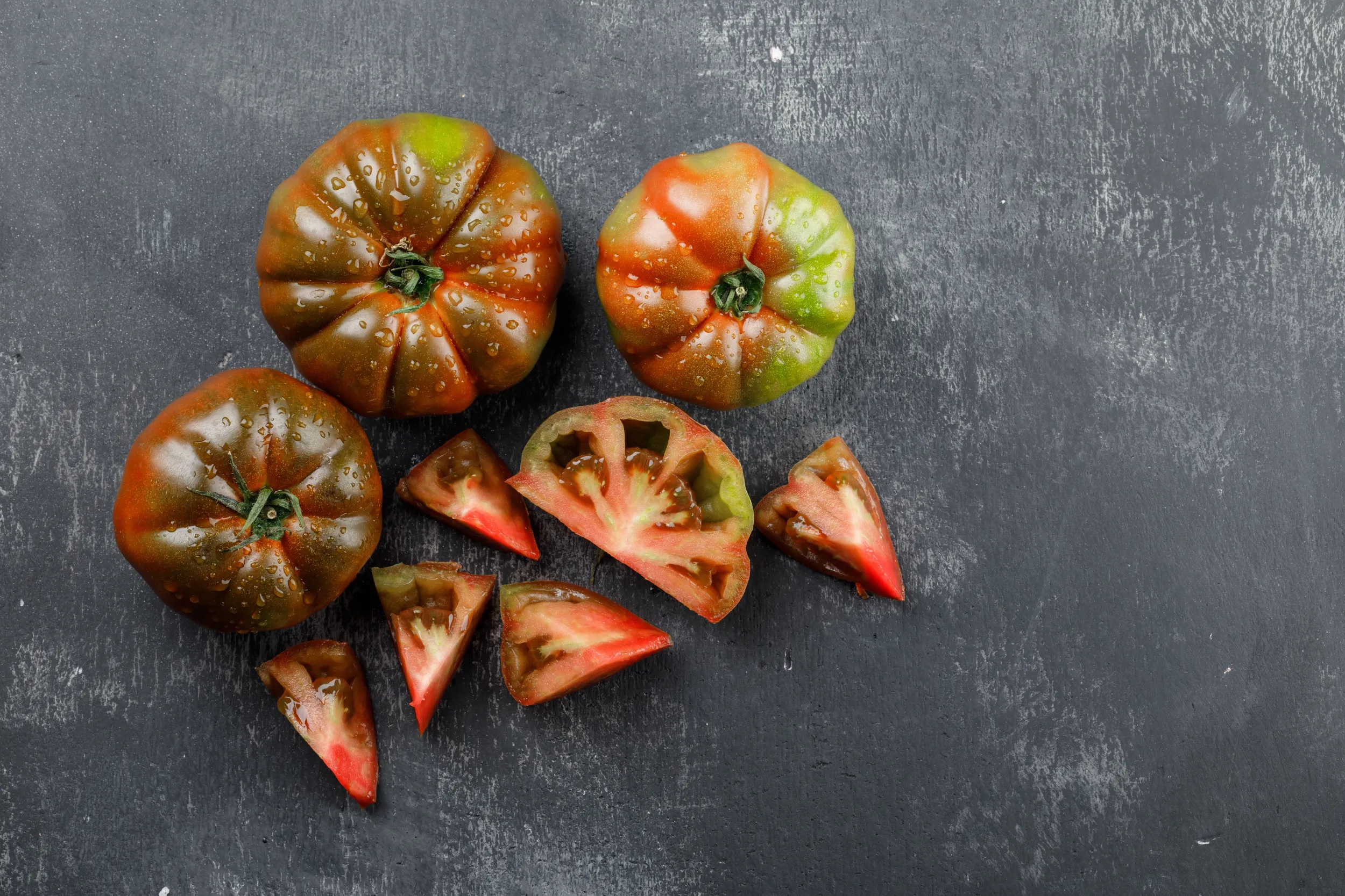 kumato-tomatoes-with-slices-top-view-grungy-grey-wall
