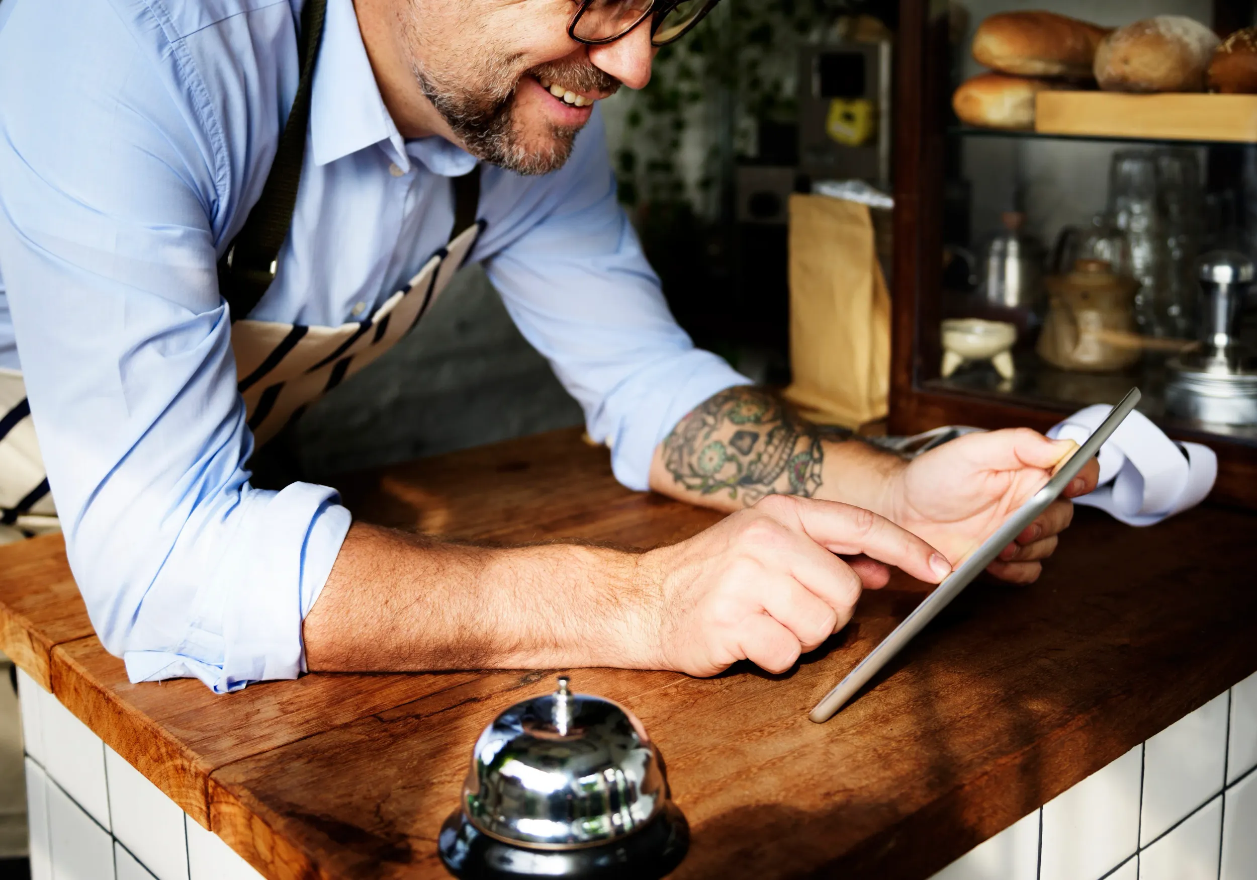 tattooed-man-using-digital-tablet-baker-s-shop