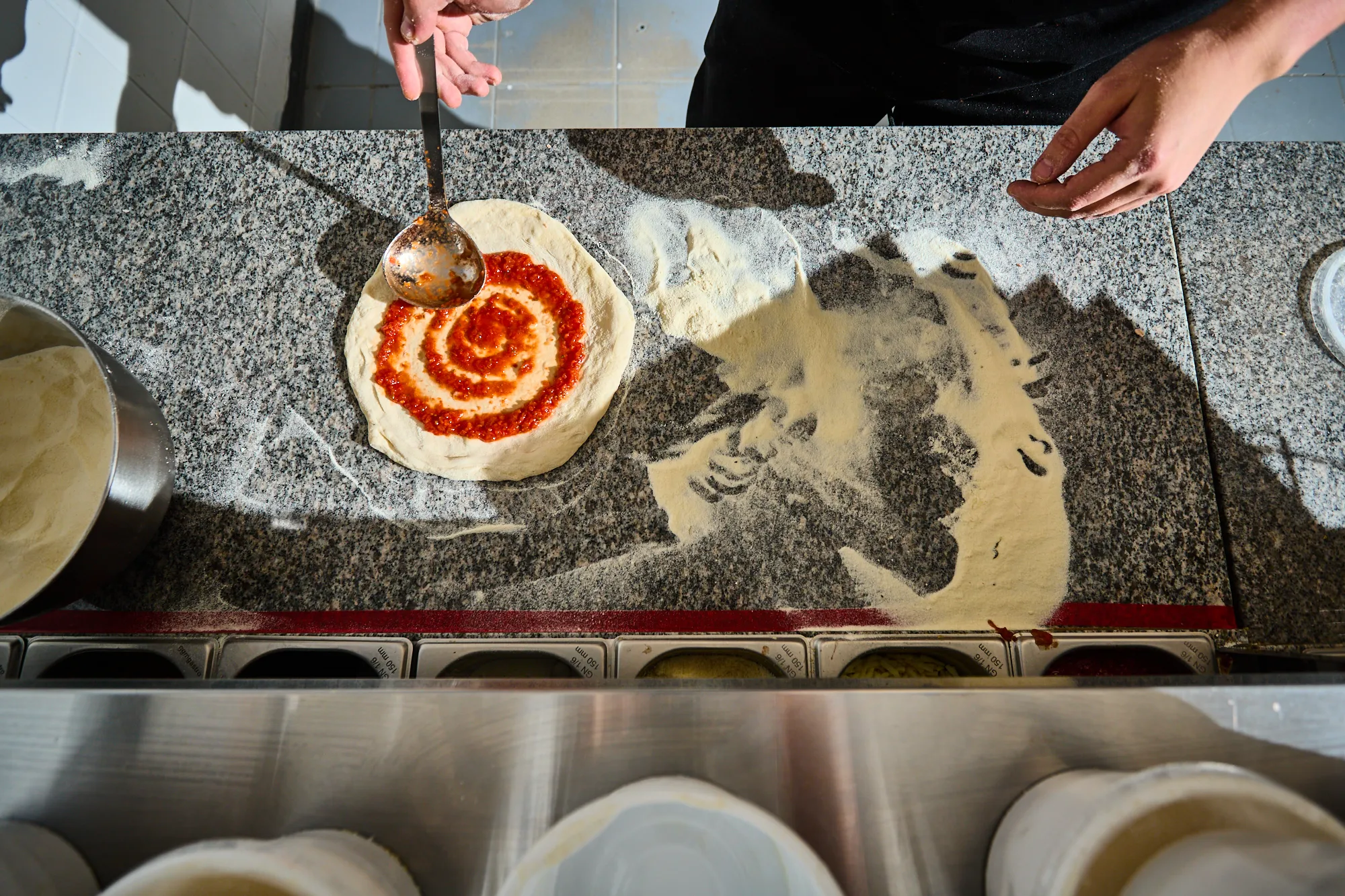 Készül a pizza, a tésztára rákerül a szósz